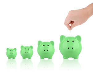 Saving money concept - Growing savings. Hand putting coin into piggy bank