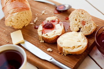 Toasts with jam on plate and cup of tea on bright background