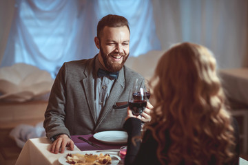 Beautiful young couple with glasses of red wine in luxury restaurant