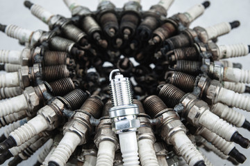 Spark plug on a background of used spark plugs arranged in a circle at a shallow depth of field