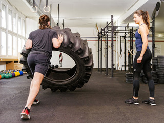Fototapeta na wymiar Couple working out with tire at crossfit gym