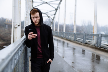 Sporty man using his mobile phone on bridge