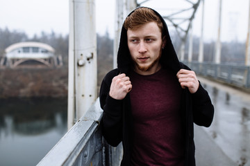 Portrait of sporty man on bridge in the hood