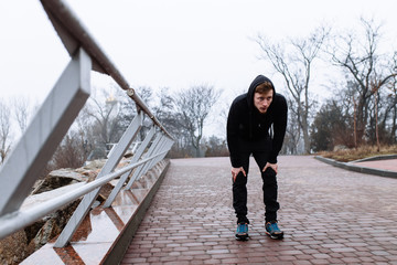 Sporty man break after jogging through rainy cityscape