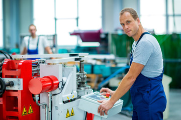 young worker in factory using machine