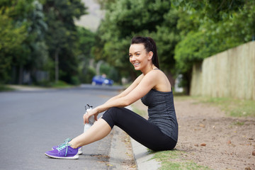 Smiling sports woman sitting outdoors after workout