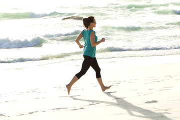 Young woman running along the sea shore