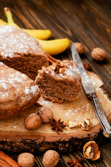 
pastries, cake with walnuts and a banana with powdered sugar on a wooden background