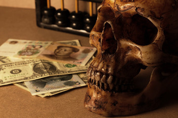 skull on old wood with banknote yuan and dollar