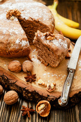 
pastries, cake with walnuts and a banana with powdered sugar on a wooden background