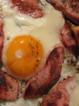 Appetizing cooked fried eggs with sausages and black hot pepper