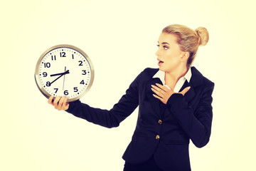 Young businesswoman terrified looks at the clock