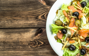 Mediterranean salad with salmon and olives on wooden background with copy-space