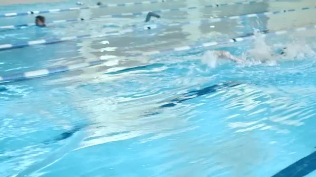 Professional Male Swimmer Jumping Off the Starting Block and Performing the Butterfly Stroke. Camera Follow Him. Shot on RED Cinema Camera.