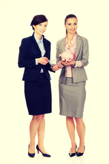 Two businesswomen with piggy bank.