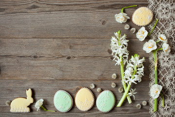 Easter wooden background with flowers hyacinths and daffodils, cookies in the form of eggs and rabbits