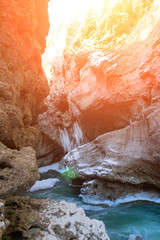 Stone canyon of a mountain river with blue water in winter bathed in sunlight. Toned photo