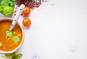 Tomato soup with meat in a white bowl on a white wooden backgrou
