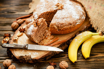 Fototapeta na wymiar pastries, cake with walnuts and a banana with powdered sugar on a wooden background