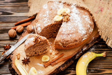 
pastries, cake with walnuts and a banana with powdered sugar on a wooden background