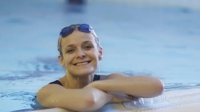 Happy Professional Female Swimmer in Goggles Getting out the Water in Swimming Pool Shot on RED Cinema Camera.