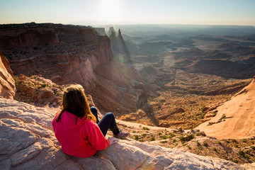 Girl sitting at the Mesa Arch at sunrise, Canyonlands