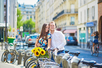 Young romantic couple using bicycles in Paris, France