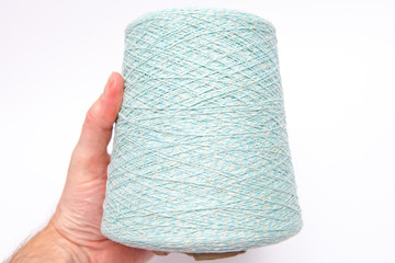 The hand holds a skein of colored wool threads