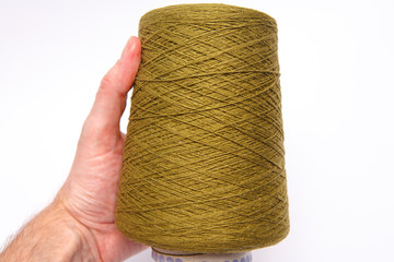 The hand holds a skein of colored wool threads