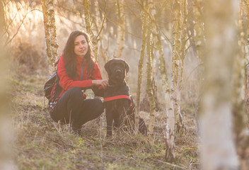 Girl sitting with dog in birch forest