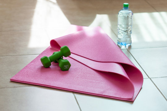 Two  dumbbells with mineral water on  yoga mat