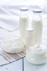Obraz na płótnie Canvas Dairy products. Milk in glass bottle, yogurt, sour milk cheese, sour cream in glass jar, on light blue wooden table