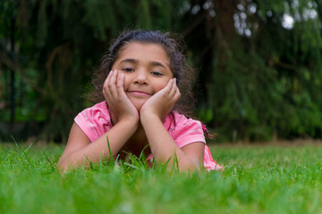 Naklejka na ściany i meble Small gypsy child girl lay in grass having head in hands