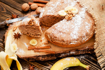 
pastries, cake with walnuts and a banana with powdered sugar on a wooden background