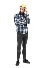 Serious young hipster holding straw hat visor looking at camera. Full body length portrait isolated over white studio background.