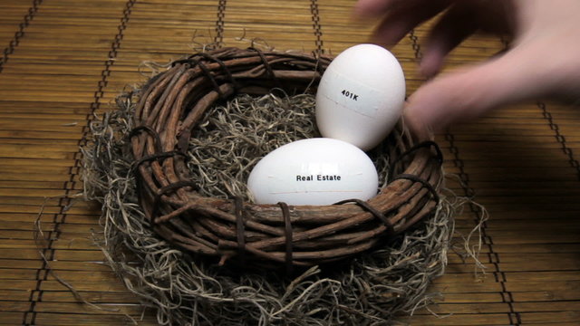 Hand adding egg labeled with 401K to retirement nest with real estate egg.
