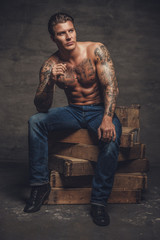 Shirtless muscular man with tattooes on his body.