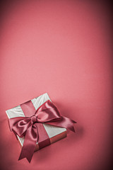 Gift box with tied ribbon on red background holidays concept