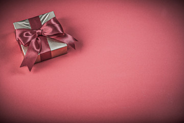 Present container with tied bow on red background holidays conce