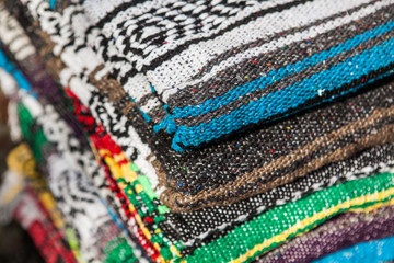 Colorful Mexican serapes hang in row. 
