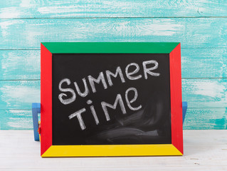 Blackboard with text it's summer time on wooden deck