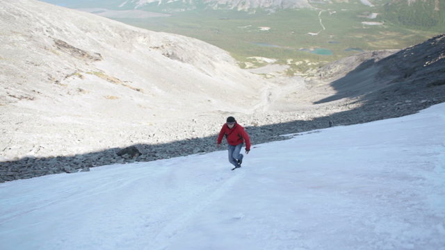 Young man a hiker climbing snow steep slope in mountains. Khibiny massif, Kola peninsula, Russia
