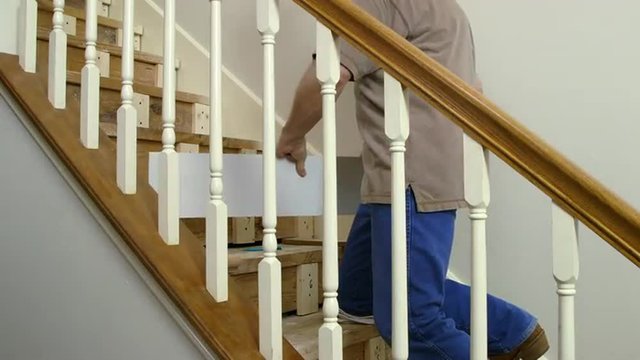 A tradesman or handyman homeowner type fitting in a new riser during a home staircase renovation project.
