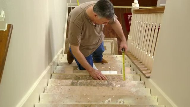 A tradesman or handyman homeowner type fitting in stair riser and measuring for the tread portion of the step.