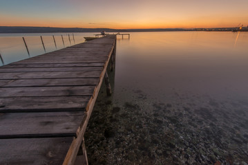 Beauty and calm sunset on lake with wooden pier .