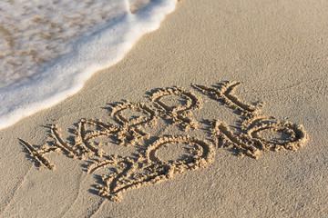 Inscription Happy 2016 on sandy beach with wave's foam