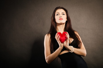 Beautiful woman holds red heart on black