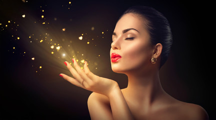 Beauty young woman blowing magic dust with golden hearts