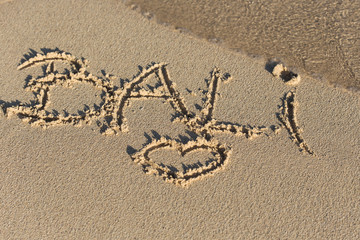 Inscription Bali and shape of heart on sandy beach with wave's f