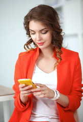 Beautiful businesswoman using cell phone standing in office